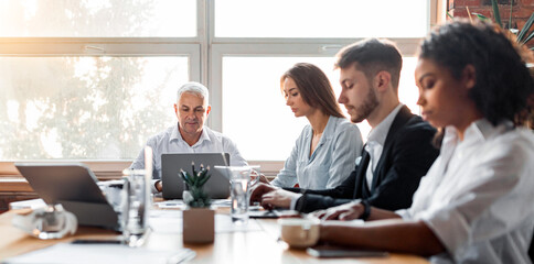 Business Lifestyle. Serious Colleagues Working During Corporate Meeting Sitting Together At Desk In Office. Selective Focus, Panorama