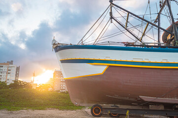 This photograph, taken on October 25, 2024, showcases a boat anchored in the sand of Navegantes, SC, Brazil, during a serene late afternoon. The setting sun