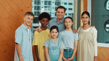 Happy teacher and diverse student standing while smilling to camera. Professional smart instructor with highschool children with mixed races in casual outfit pose at camera with cheerful. Edification.