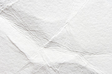 Close-up of crumpled white paper texture with wrinkles and folds for creative background designs.