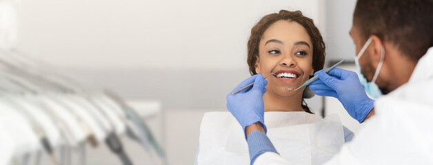 Pretty black lady in dentist chair looking at her doctor with smile, close up