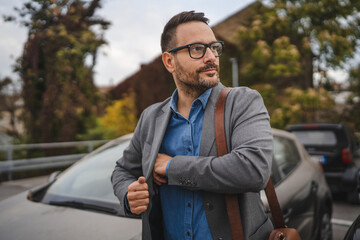 Portrait of businessman puts the phone in pocket at parking lot