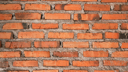 A close-up view of a rustic brick wall, showcasing the texture and warm tones of the red bricks, with visible mortar and slight wear, perfect for backgrounds or architectural themes.