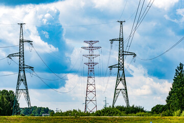 A view of electric power transmission lines stretching across a cloudy sky and scenic landscape in the countryside