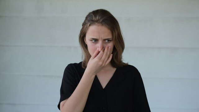 portrait of a young woman covering her nose from a sharp stinking smell