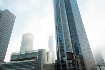 Fototapeta premium Beautiful modern metropolis in the fog with business and office buildings and the Palace of Culture in Warsaw. Amazing foggy city of Warsaw with sun, Poland on a cloudy, overcast day. Urban wallpaper