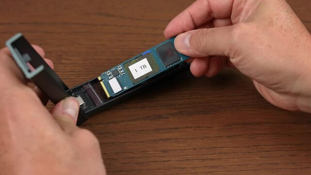 A close-up view installing an M.2 NVMe SSD drive into an external USB enclosure.  	