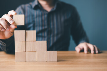 hand of a businessman stacking wood empty ten blocks with copy space for text or symbols, development concept for growth success process.