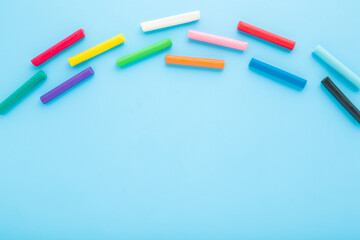 Multicolor modeling clay sticks on light blue table background. Pastel color. Closeup. Empty place for text. Top down view.