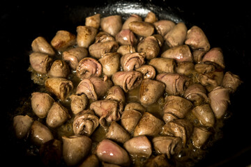 Crispy fried chicken hearts in a pan, cooked in butter. Rich taste and texture for traditional or gourmet recipes.