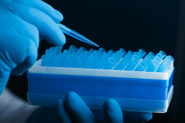 A scientist's hand in glove holds a pipette