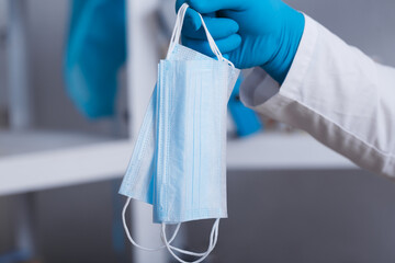 A hand in a medical glove holds a medical mask