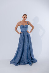 Fototapeta premium Full-length photo of a cute girl in a lush dress with a train on an isolated background. Fashionable stylish clothes. Wedding trends 2025