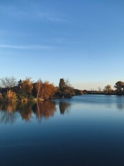 Autumn river shore landscape, calm panoramic view, blue and brown, water reflection