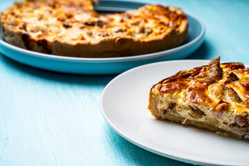 Quiche Laurent according to a traditional French recipe. Pie with chicken and mushrooms on a blue plate with a light blue napkin on a blue background.