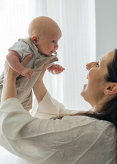 Mother enjoys playing with her infant, spending time together, concept of family and childcare....