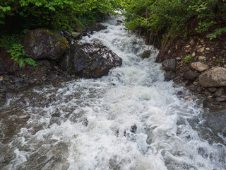 A mountain river with raging waters forming a natural crossing, surrounded by picturesque rocks and...
