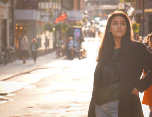 Fototapeta premium A young woman standing in the city with a street in the background