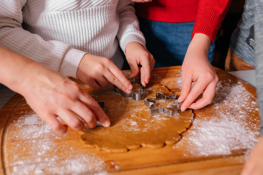 Cooking Christmas cookies with family. Father Mother and daughter hands top view on making gingerbread biscuits with cookie cutters, with New Year Christmas decoration