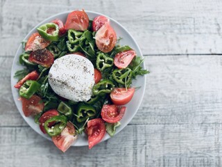 Green salad of arugula, tomatoes and burrata on the table.
