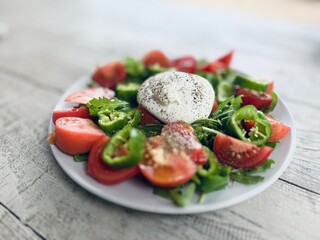Green salad of arugula, tomatoes and burrata on the table.

