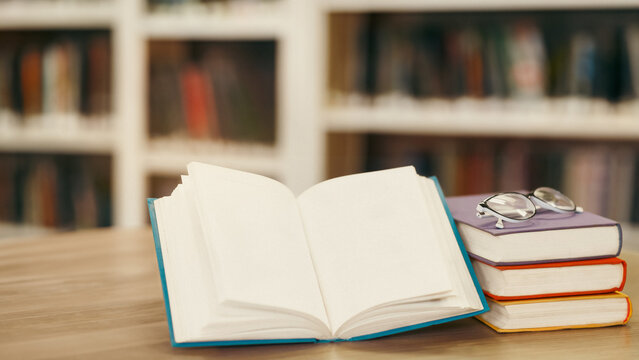 Educational Concept. Close up of opened book with bookshelf in the background, selective focus, copyspace, mock up