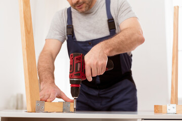 Cropped Shot Of Professional Carpenter Using Drill Assembling Wooden Table Indoor. Unrecognizable Craftsman Making Desk Working And Making Furniture. Professions, Craft Career And Occupation