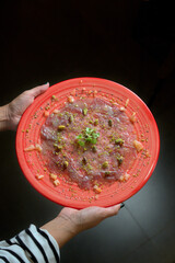 Tuna Carpaccio on Red Plate Garnished with Pistachio Dust