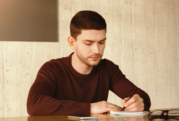 Young Man Taking Notes Working Sitting At Work Desk In Office. Selective Focus