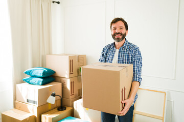 Joyful man happily moving a cardboard box into his new apartment, representing a fresh beginning...