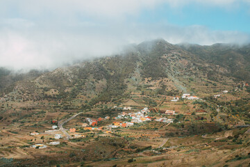 Berglandschaft mit Dorf und Feldern unter Wolkenhimmel, Teneriffa