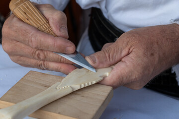 Romania, Suceava, September 21, 2024. A close-up of a craftsman’s hands skillfully carving a wooden spoon, showcasing the precision and artistry involved in traditional woodwork.