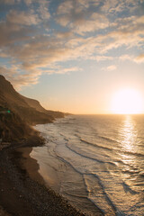 Atemberaubender Küstenblick bei Sonnenuntergang mit Bergen und Meer