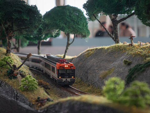 Ponferrada, Leon, Spain; 10-20-2024: Exhibition of railway models in which a Renfe locomotive pulling wagons takes a curve surrounded by stones and trees and a shepherd with sheep