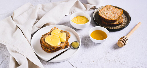 Morning sandwiches on grain bread with honey butter on a plate on the table web banner