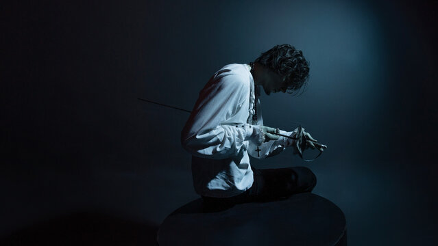 A dramatic hero with a sword in his hands, suffering from defeat and injury, a portrait in the moonlight, drama or theater