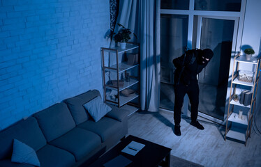 Housebreaking Concept. Intruder sneaking into house at night, holding crowbar, top view from above...