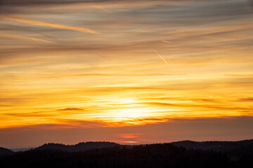 Fototapeta premium Zoomed-in view of a cloudy yellow sunset behind the French mountains