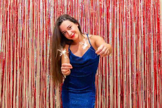 Woman in blue dress holding sparklers at New Year's Eve party