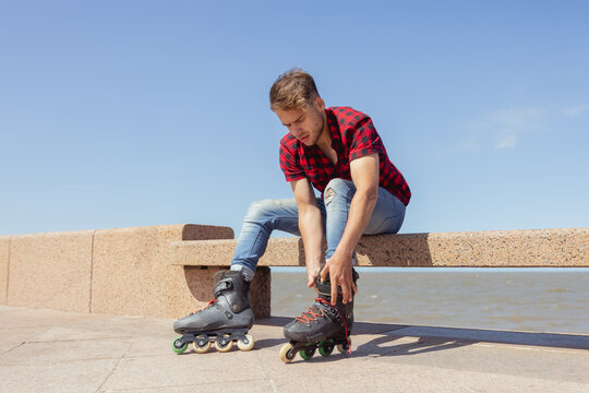 Young man tying his inline skates by the seaside