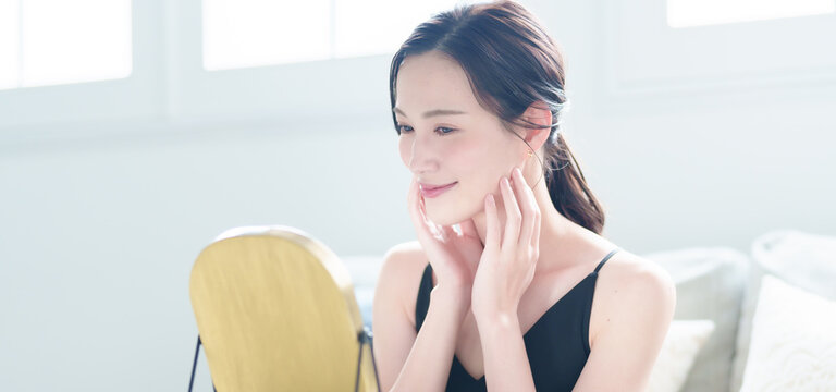 リビングでお肌をケアする女性　スキンケア　ビューティー　コンセプト