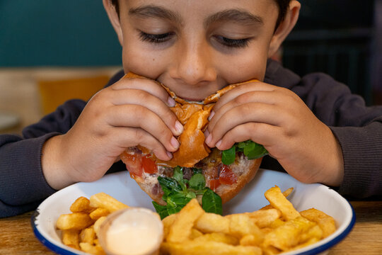 Child enjoying a burger with chips on a table