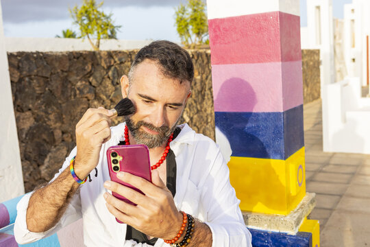 Transvestite gay man applying makeup outdoors