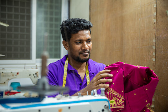 Tailor working on clothes with machine.