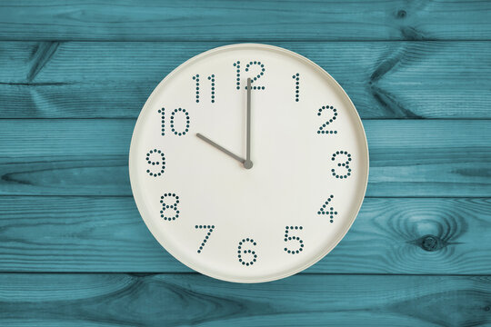 Round white wall clock at 10 o'clock on turquoise celadon wood background. concept of daily regime or morning time