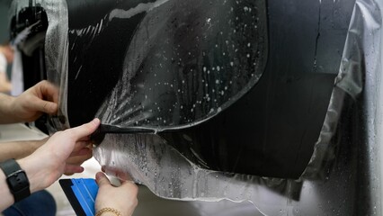 Mechanics applying protective film on car headlight