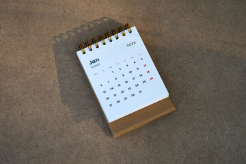 January 2025 - Top view of a small desktop calendar with wooden table background, time and business concept
