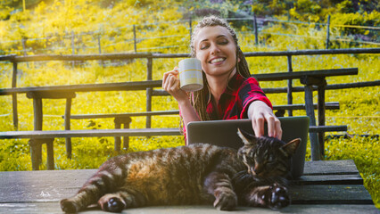 Freelancer woman enjoying coffee and petting cat while working o