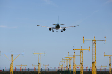 Ein Flugzeug von hinten im Landeanflug auf einen Flughafen mit Anflugbefeuerung. 