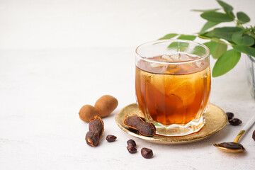 Glass of tasty tamarind drink and fruits on white background